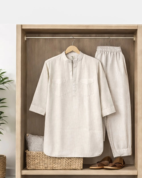 White shirt and pants hanging on a wooden rack with a plant in the background